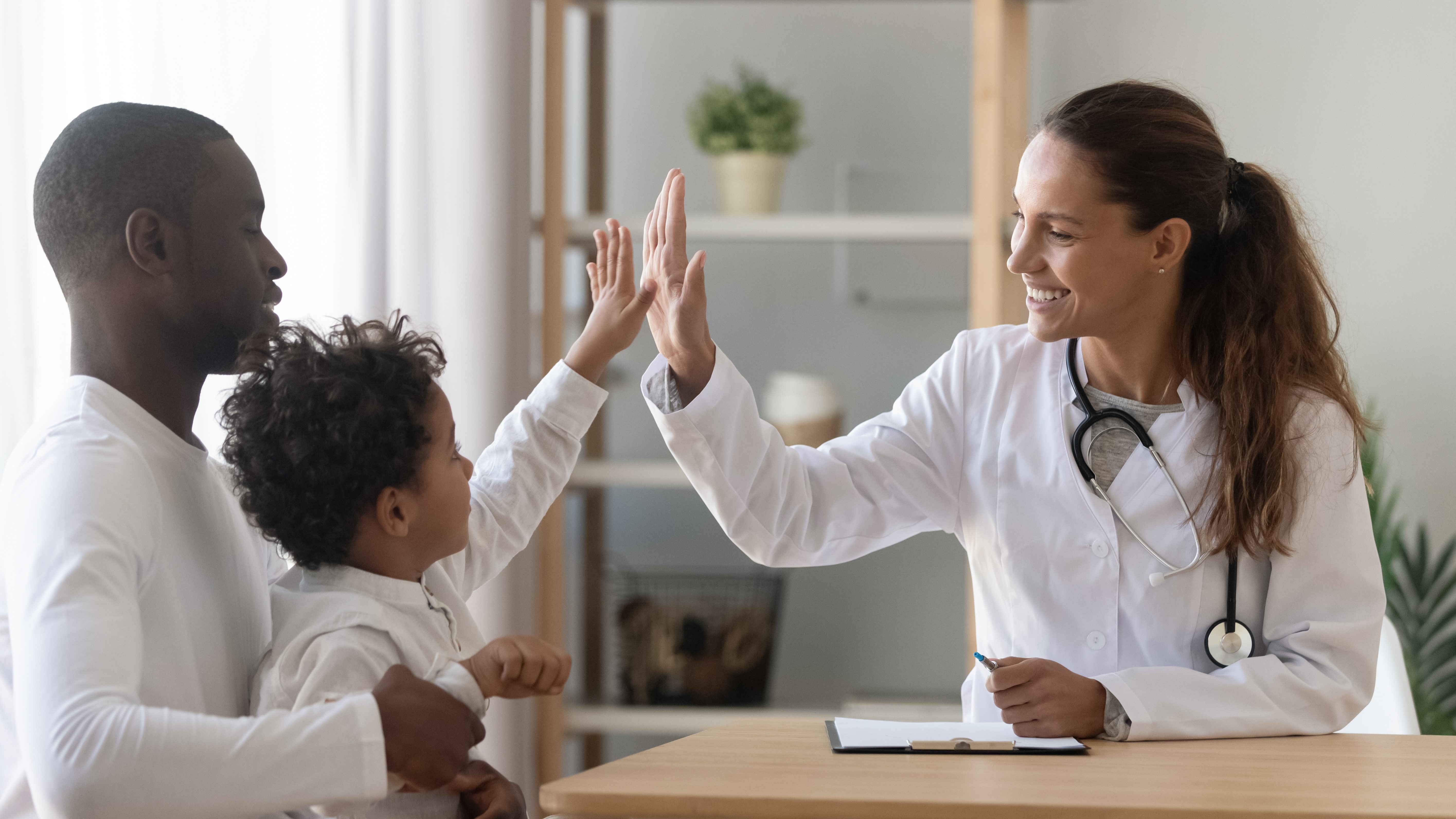 Banner image of healthcare provider giving high five to child patient
