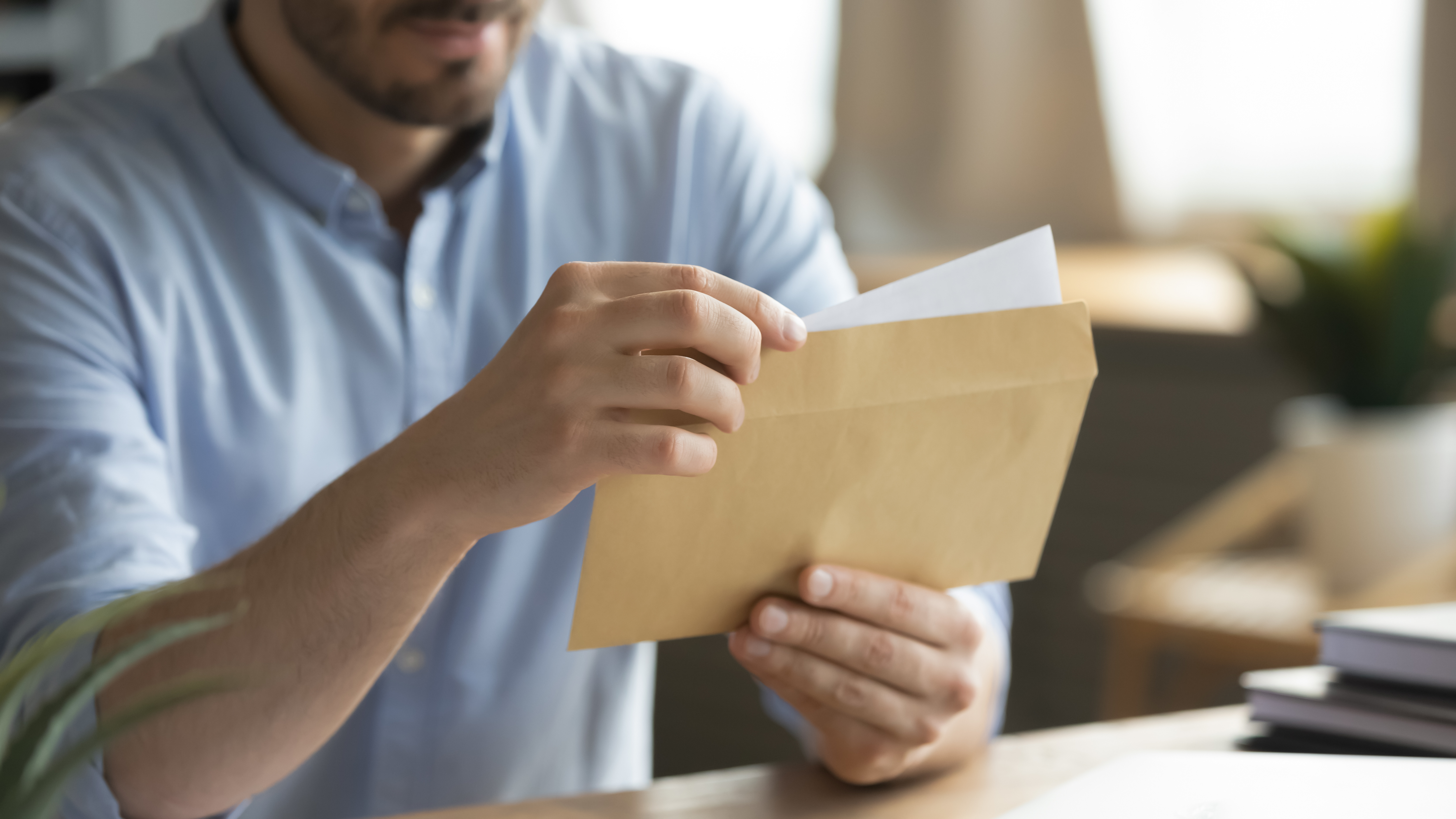 Adult man holding up an envelope letter and reading it