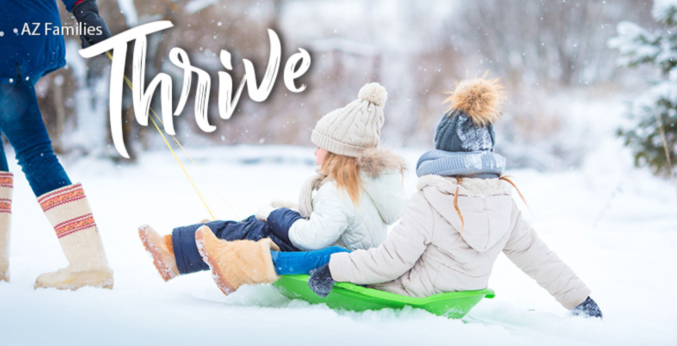 AZ Thrive Newsletter of a parent pulling her two girls on a sled in the snow